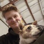 Carrera holding a small brown and white dog